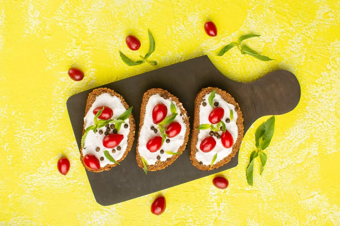 Draufsicht auf Brot mit Creme sowie Hartriegel auf der gelben Oberfläche.